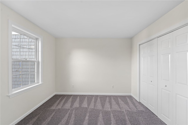 unfurnished bedroom with carpet floors, baseboards, and a closet