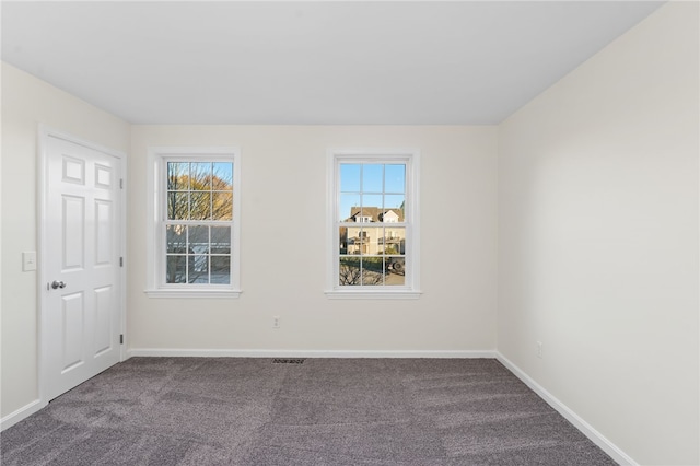 carpeted empty room featuring visible vents, a wealth of natural light, and baseboards