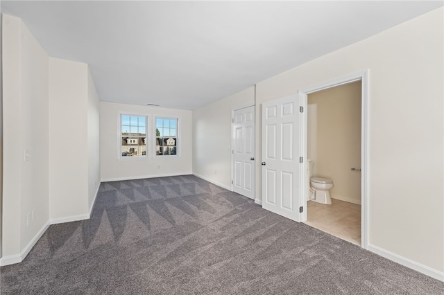 spare room with dark colored carpet and baseboards