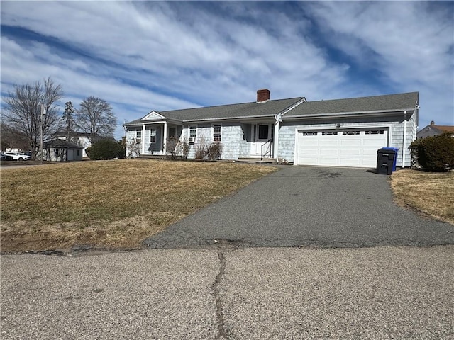 single story home featuring a garage, a front lawn, a chimney, and driveway