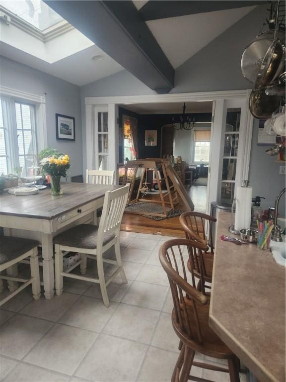 dining area with light tile patterned floors and vaulted ceiling with skylight