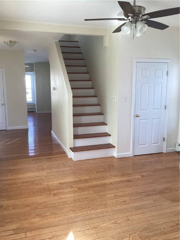 staircase with ceiling fan, baseboards, and wood finished floors