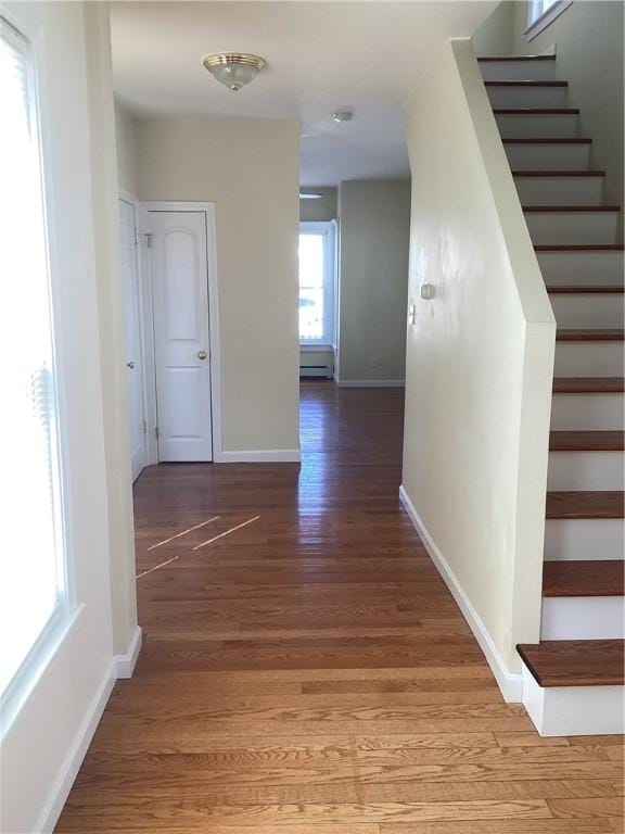 corridor featuring baseboards, stairway, and light wood finished floors