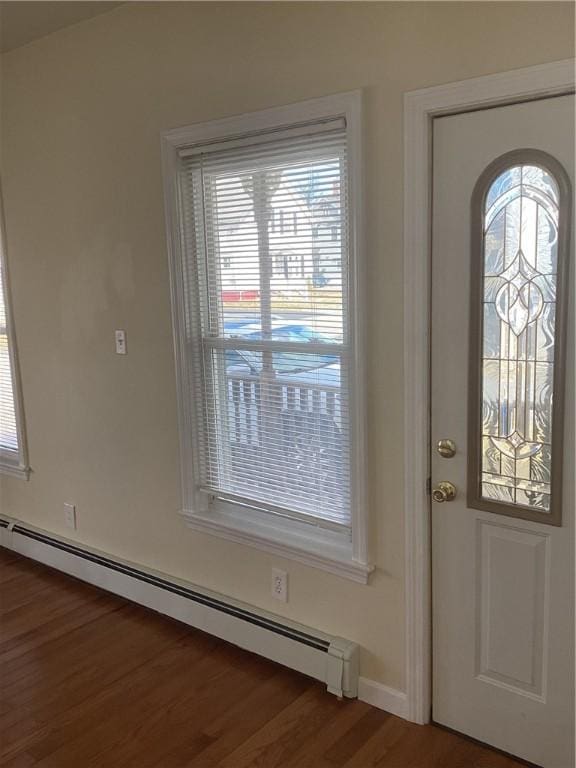 foyer with a baseboard heating unit and wood finished floors