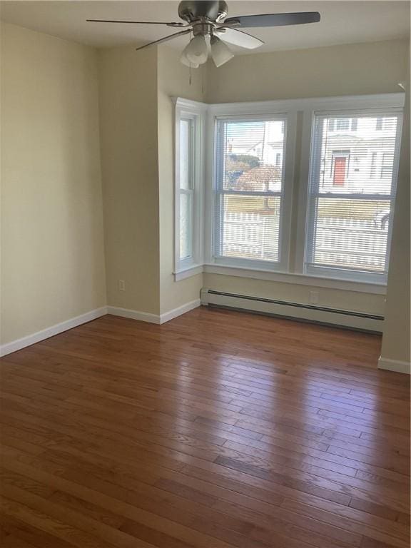 spare room featuring a ceiling fan, wood-type flooring, baseboards, and baseboard heating