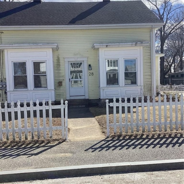 doorway to property featuring roof with shingles and fence