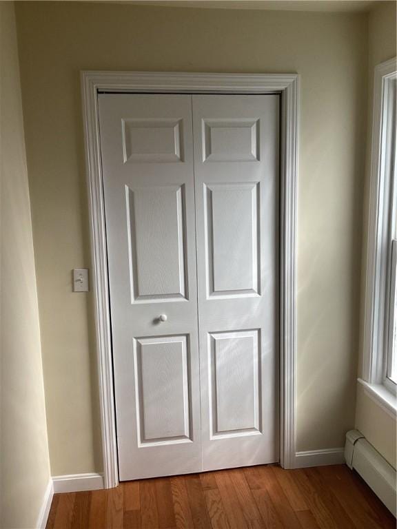 room details featuring a baseboard radiator, baseboards, and wood finished floors