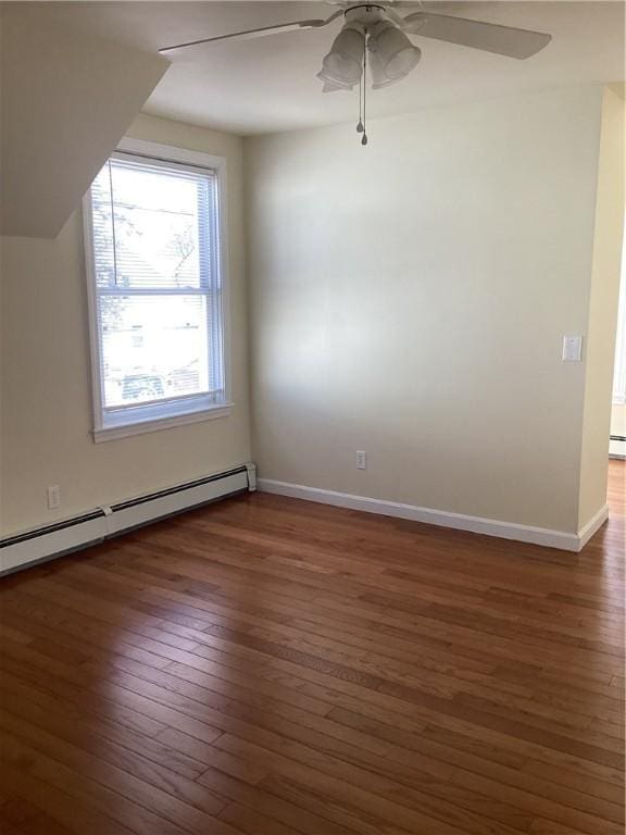 spare room with dark wood-style floors, a baseboard heating unit, ceiling fan, and baseboards