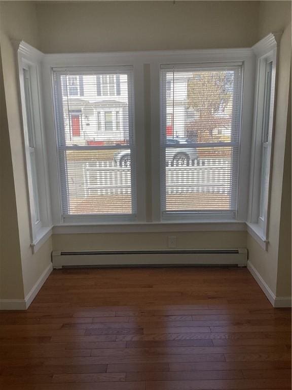 unfurnished room featuring hardwood / wood-style flooring, baseboards, and a baseboard heating unit