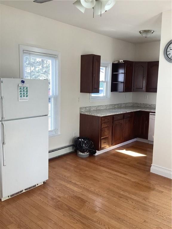 kitchen with open shelves, light countertops, light wood-style flooring, a baseboard heating unit, and white appliances