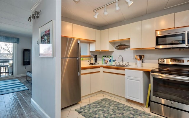 kitchen with light wood-type flooring, stainless steel appliances, a sink, and light countertops