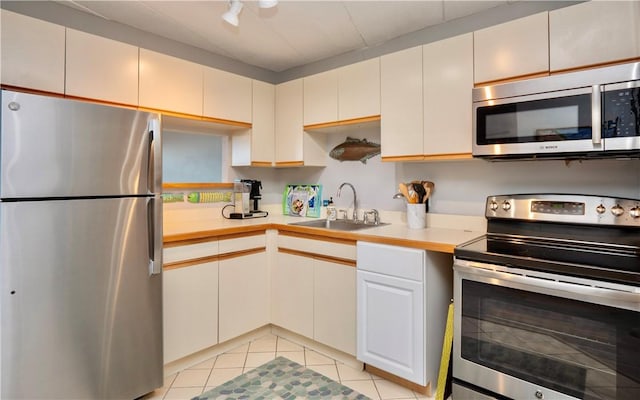 kitchen featuring light tile patterned floors, appliances with stainless steel finishes, light countertops, and a sink