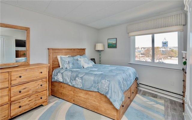 bedroom featuring a baseboard heating unit and wood finished floors