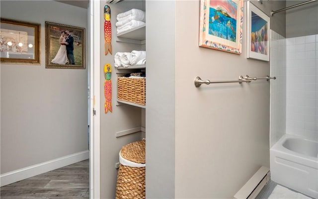 full bathroom with a baseboard heating unit, shower / tub combination, baseboards, and wood finished floors