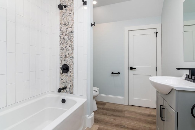 bathroom featuring baseboards, bathing tub / shower combination, toilet, wood finished floors, and vanity