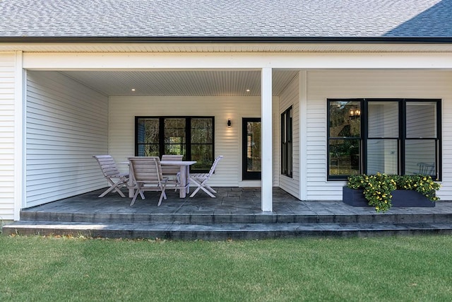 back of property featuring a shingled roof and a patio