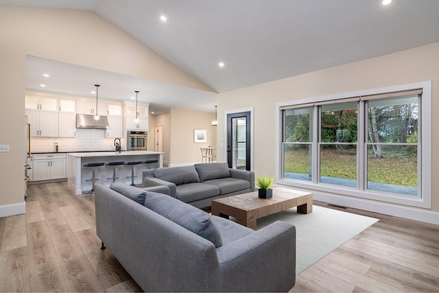 living area with high vaulted ceiling, recessed lighting, visible vents, baseboards, and light wood-style floors