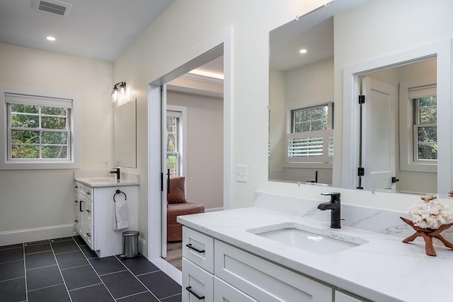 bathroom featuring a wealth of natural light, two vanities, a sink, and visible vents