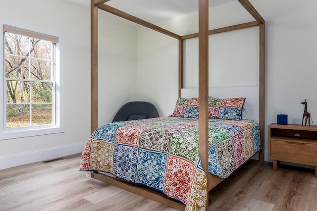 bedroom featuring visible vents, baseboards, and wood finished floors