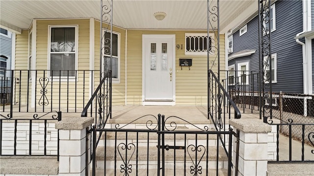 doorway to property featuring covered porch and fence