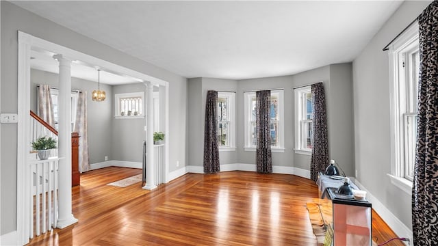 entrance foyer with ornate columns, baseboards, and wood finished floors