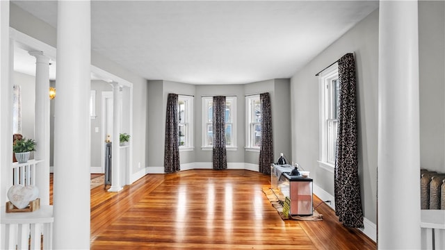 entrance foyer with wood finished floors, decorative columns, and baseboards