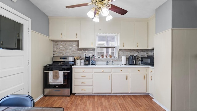 kitchen featuring black microwave, a sink, light wood-style floors, light countertops, and gas range