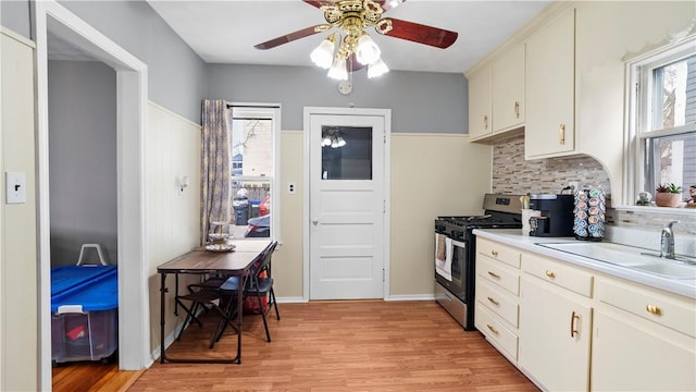 kitchen featuring tasteful backsplash, light wood-style flooring, light countertops, a sink, and gas stove