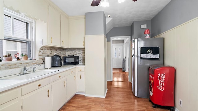 kitchen with black microwave, light countertops, a sink, and freestanding refrigerator