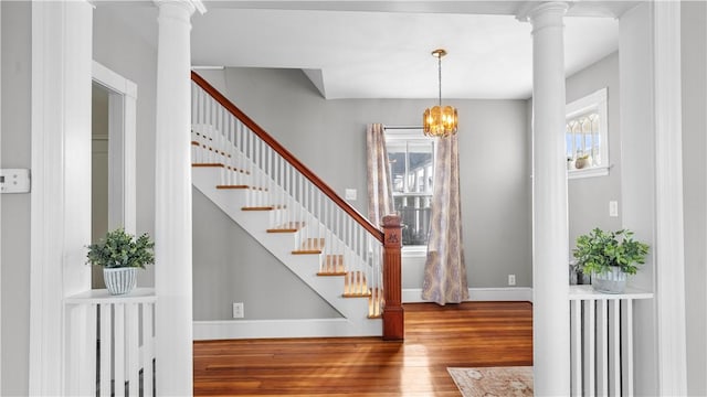 entrance foyer featuring a notable chandelier, decorative columns, baseboards, and wood finished floors