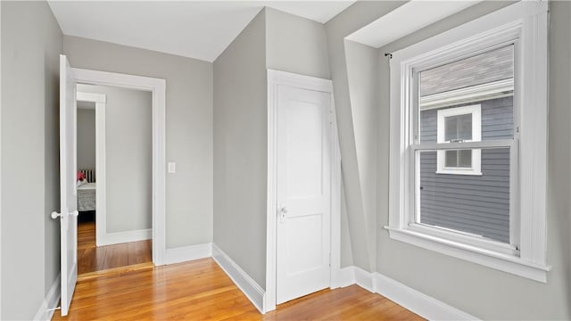 hallway with light wood-type flooring and baseboards