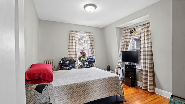 bedroom with baseboards, radiator, and light wood-style floors