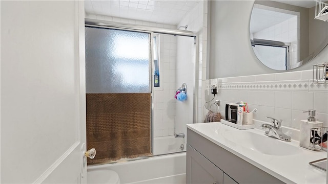 bathroom with shower / bath combination with glass door, tile walls, and vanity