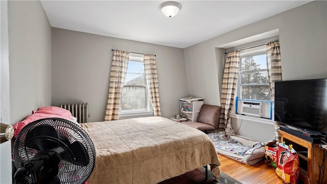 bedroom featuring cooling unit, radiator, and wood finished floors