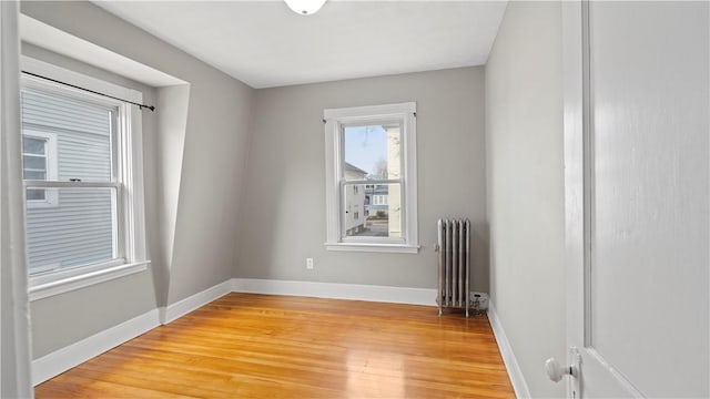 unfurnished room with baseboards, light wood finished floors, and radiator