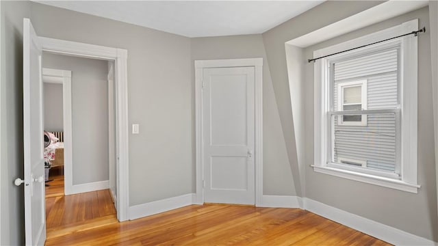 unfurnished bedroom with light wood finished floors, baseboards, and a closet