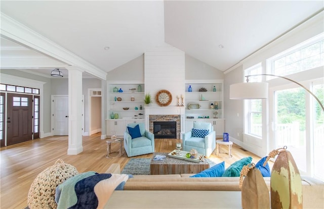 living room featuring ornate columns, light wood-style flooring, a stone fireplace, high vaulted ceiling, and baseboards