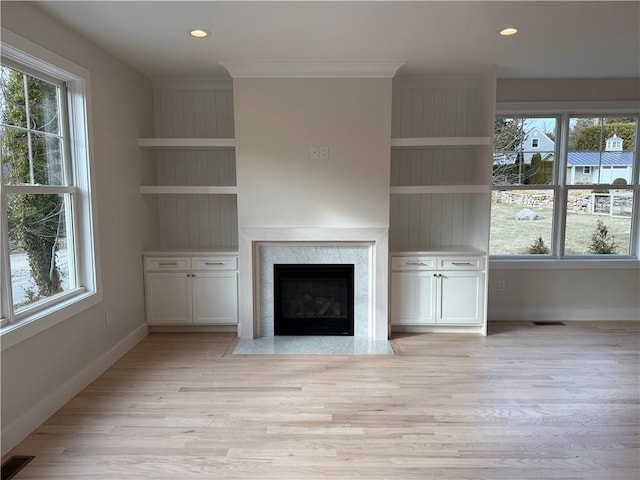 unfurnished living room featuring light wood-type flooring, visible vents, and baseboards