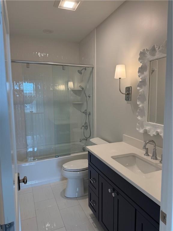 full bathroom with tile patterned floors, vanity, toilet, and bath / shower combo with glass door