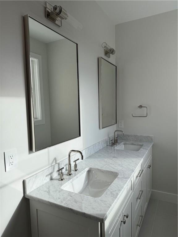 full bath featuring double vanity, baseboards, a sink, and tile patterned floors