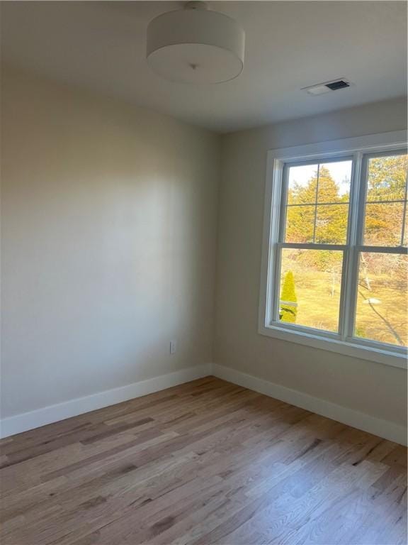 spare room with visible vents, baseboards, and wood finished floors