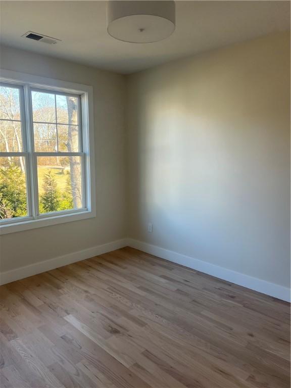 unfurnished room with baseboards, visible vents, and wood finished floors