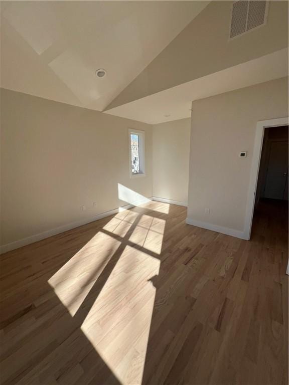 spare room with high vaulted ceiling, baseboards, visible vents, and wood finished floors