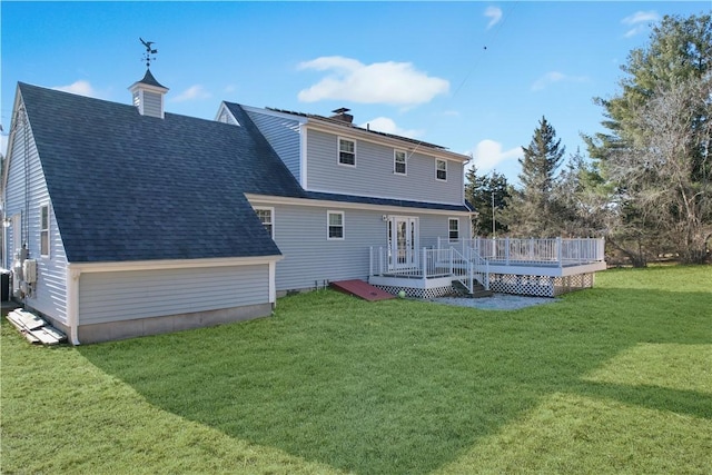 rear view of property with roof with shingles, a yard, and a wooden deck