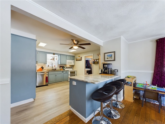 kitchen with range with two ovens, white microwave, a peninsula, a sink, and dishwasher