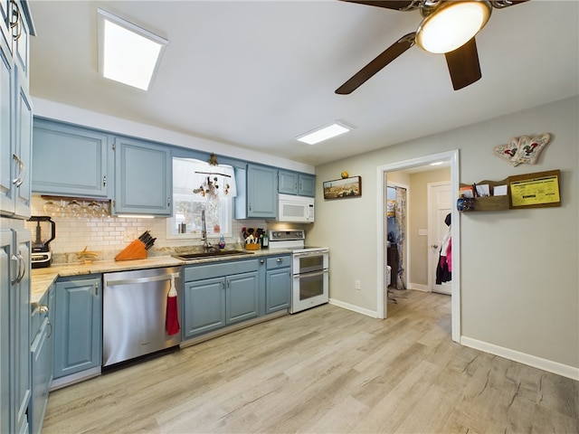 kitchen with light countertops, decorative backsplash, a sink, blue cabinets, and white appliances