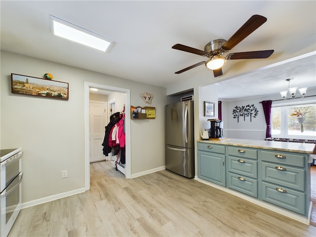 kitchen featuring a peninsula, light wood finished floors, baseboards, and freestanding refrigerator