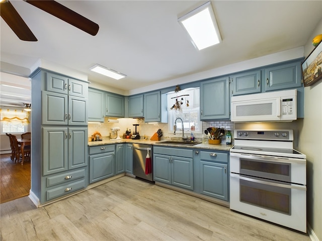 kitchen featuring tasteful backsplash, white appliances, a sink, and light wood finished floors