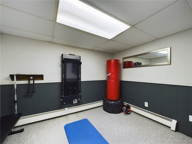 exercise room featuring a baseboard heating unit, wainscoting, a paneled ceiling, and carpet