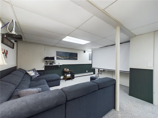 carpeted living room with a wainscoted wall, baseboard heating, and a drop ceiling